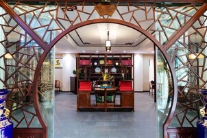 A traditional Chinese-style interior with a central table and red cushions, surrounded by glass partitions with geometric patterns.