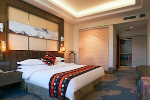 Habitación de hotel con una cama grande, una mesita de noche, un televisor montado en la pared y un armario con puerta corredera.