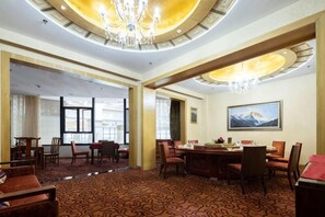 A hotel lobby with a dining area, a chandelier, and a mountain painting on the wall. - Fliport Garden Hotel Lhasa (Laha)