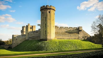 Un castillo con una torre central, rodeado de muros y varias torres más pequeñas.