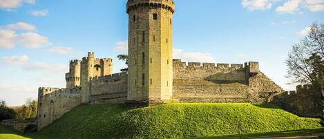 Un castillo con una torre central, rodeado de muros y varias torres más pequeñas.