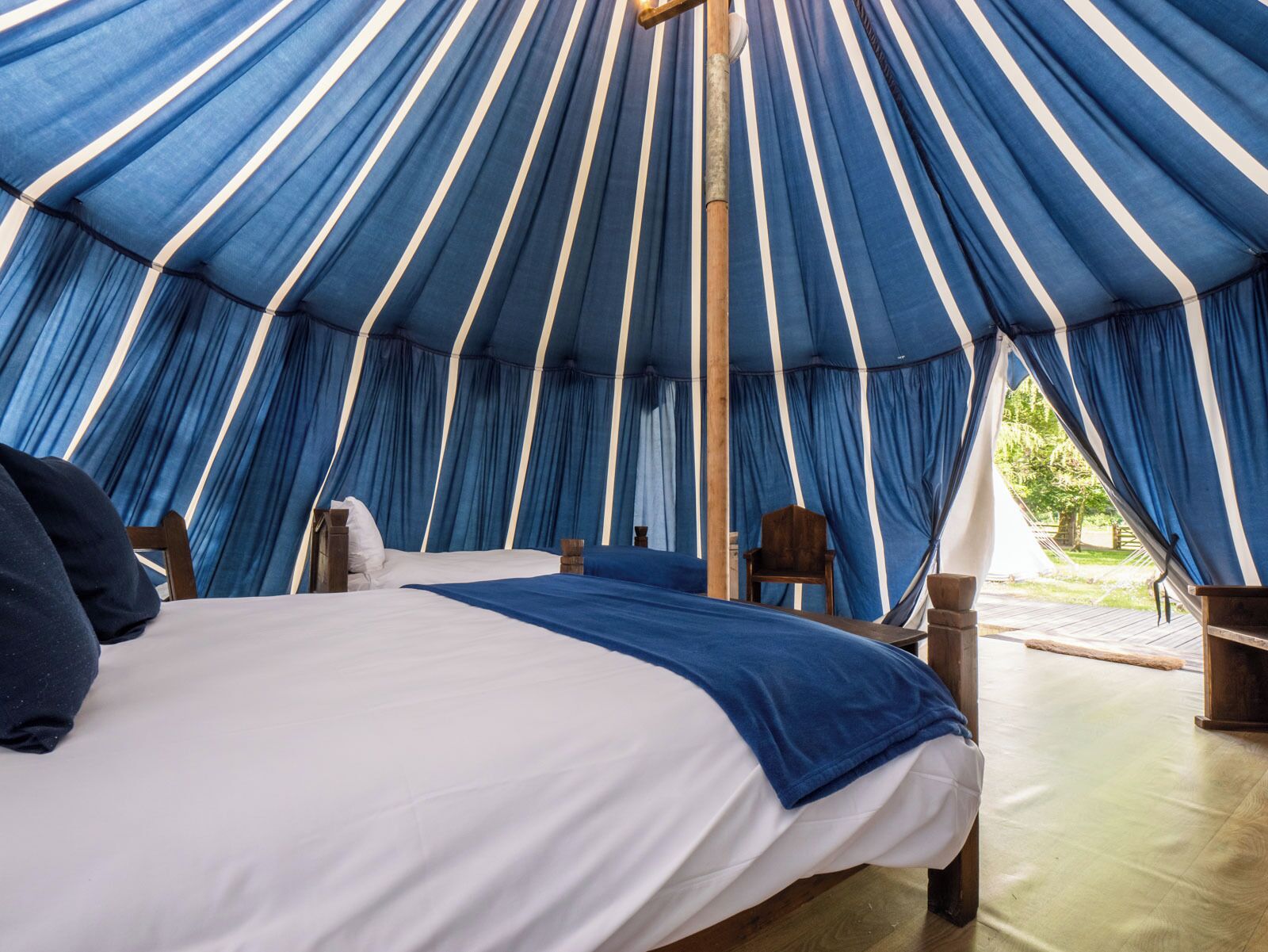 A tent with a bed, chairs, and a view of the outdoors.