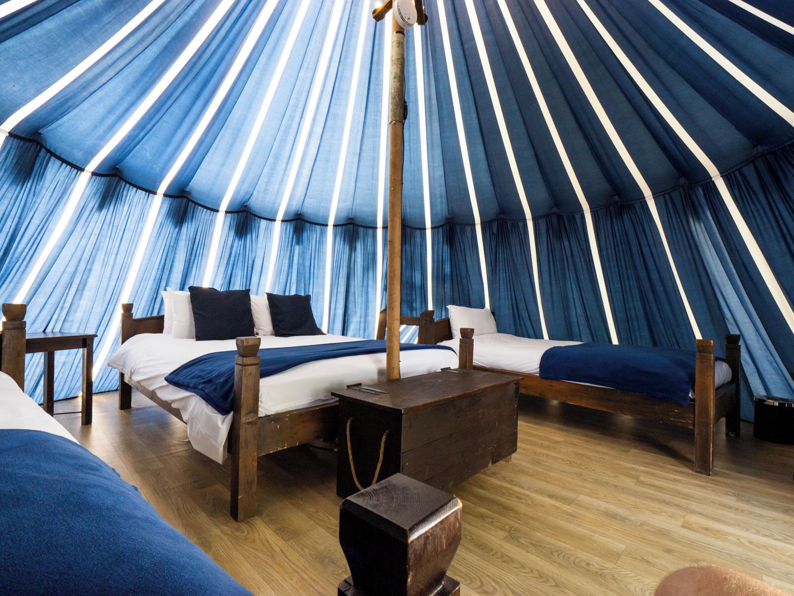 A tent-style room with a bed, wooden furniture, and a central pole structure.