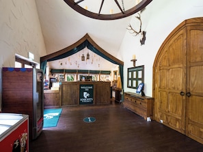 A reception area with a wooden counter, a sign reading 'Welcome to Knights Village,' and a large wooden door. - Warwick Castle Hotel and Knight's Village (Warwick)