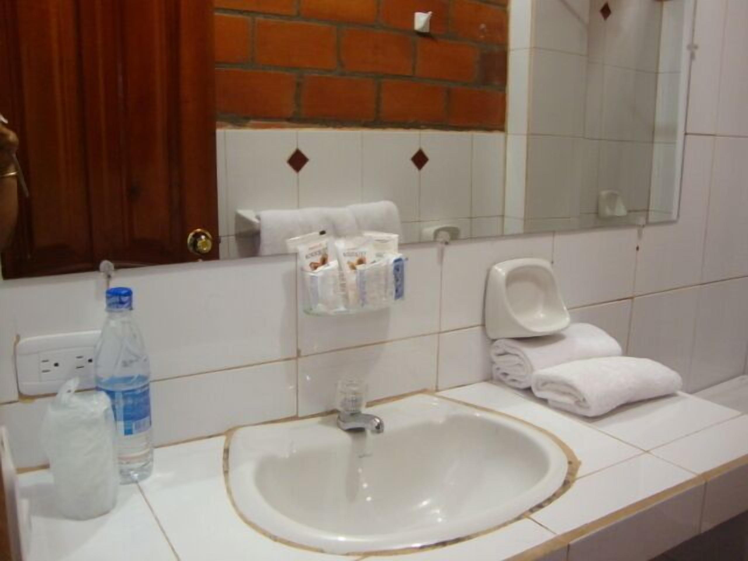 A bathroom with a sink, mirror, and toiletries.