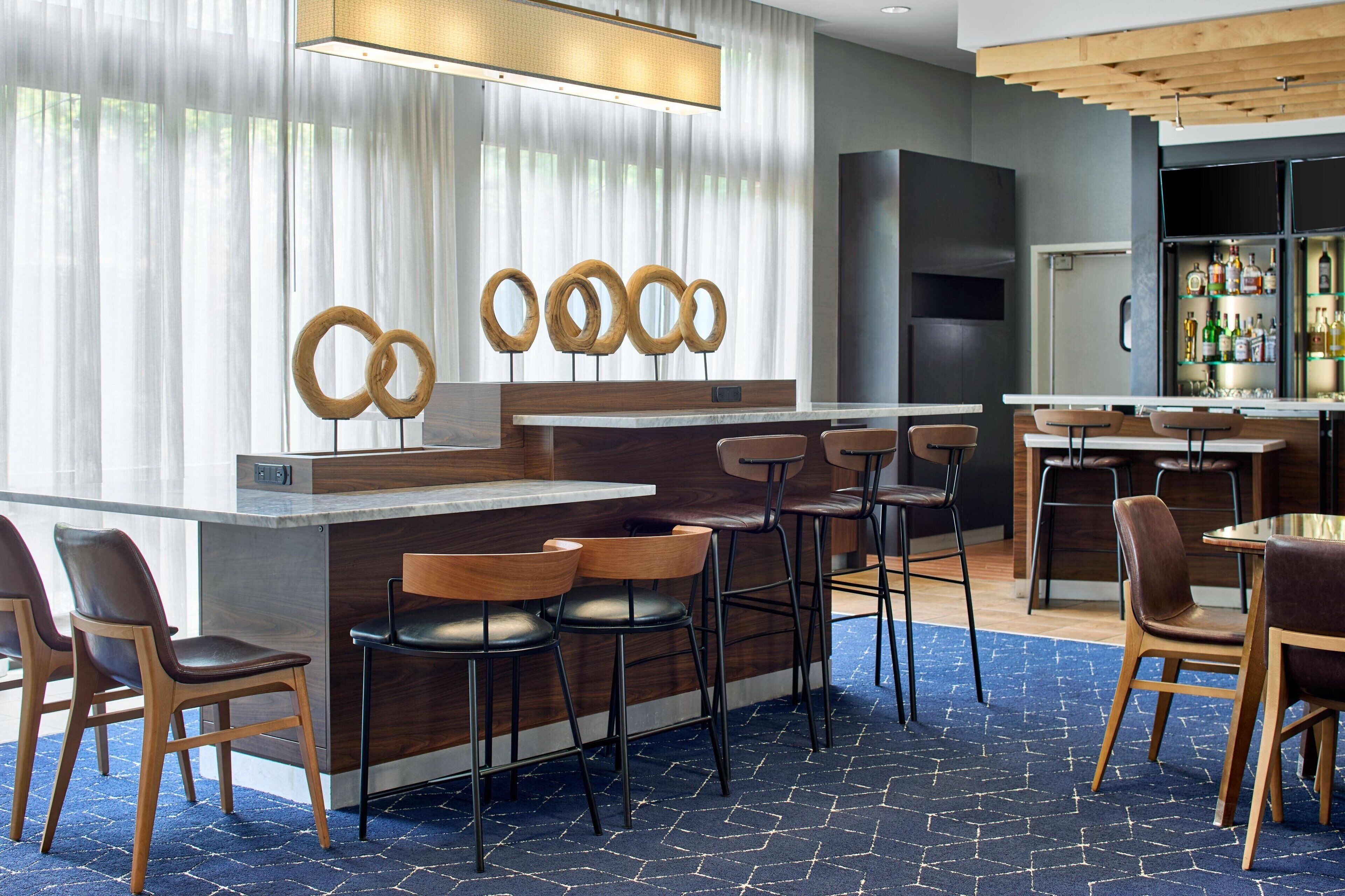 A modern bar area with a wooden counter, bar stools, and a large screen.