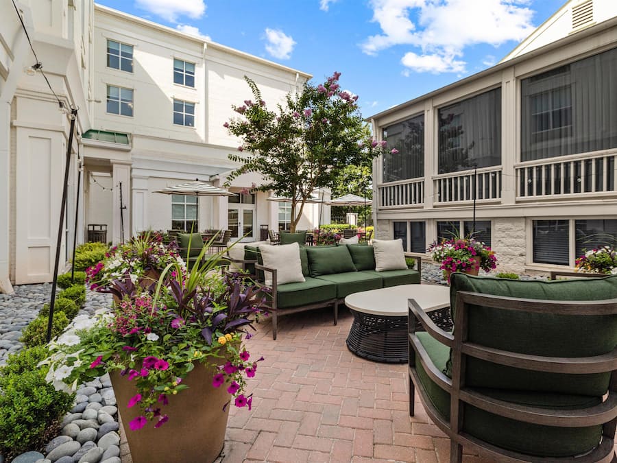 A courtyard with a green sofa, chairs, and a potted plant.