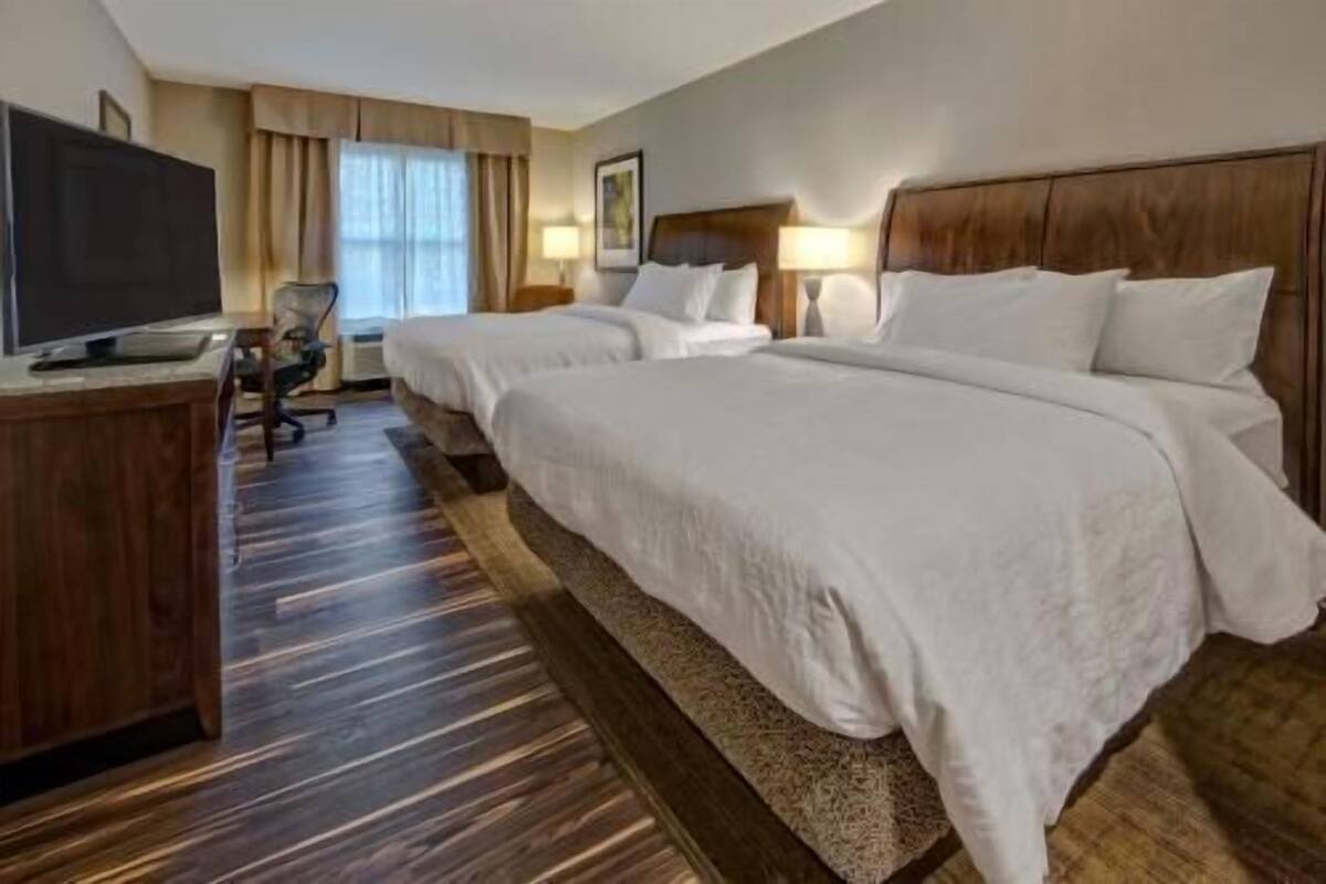 Une chambre d’hôtel avec un grand lit, un bureau avec une télévision et une chaise.