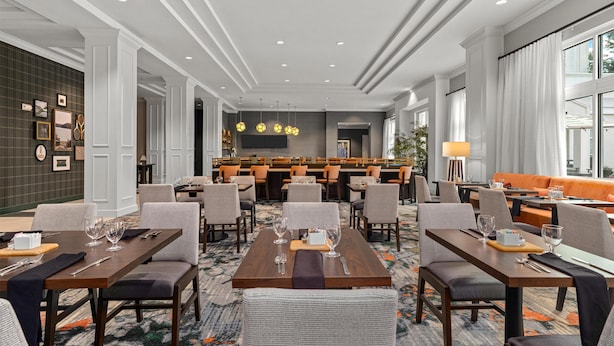 Un hall de hotel con zona de comedor, asientos y bar.