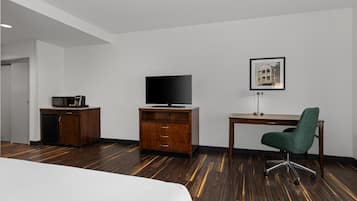 A hotel room with a bed, a desk, a television, a cabinet, and a chair.