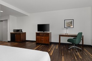 Une chambre d’hôtel comprenant un lit, un bureau, une télévision, une armoire et une chaise.