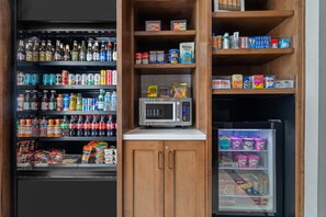 Máquina expendedora con microondas, diversas opciones de comida y bebida, y un área refrigerada.