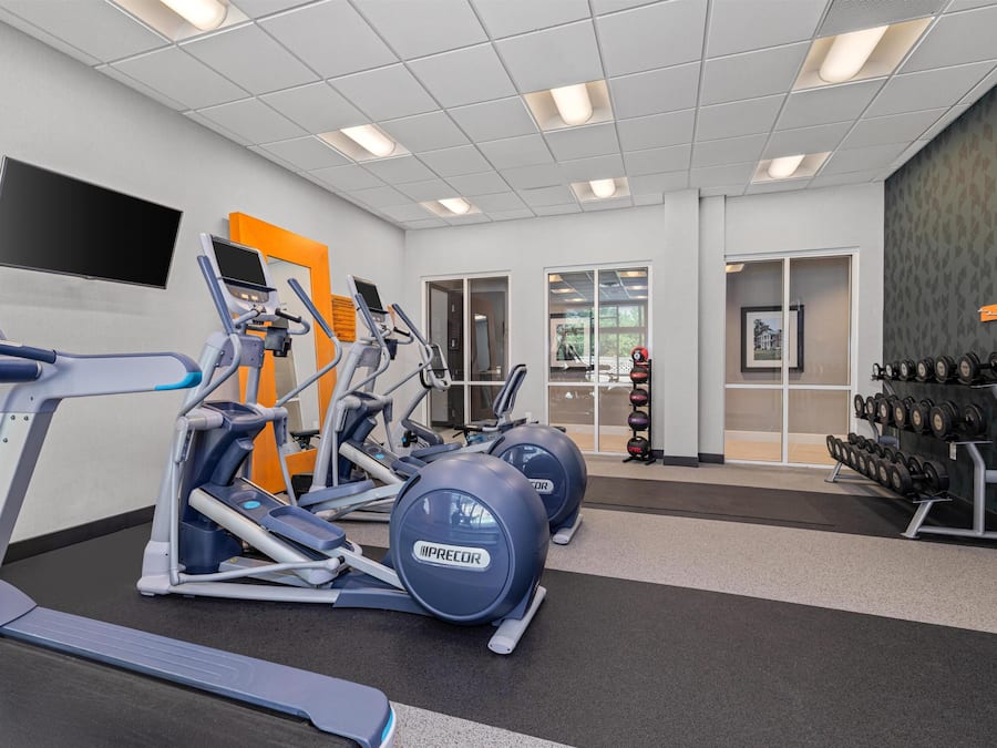 A gym with treadmills, elliptical machines, and free weights.