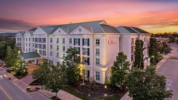 A multi-story hotel with a symmetrical facade, large windows, and a parking lot.