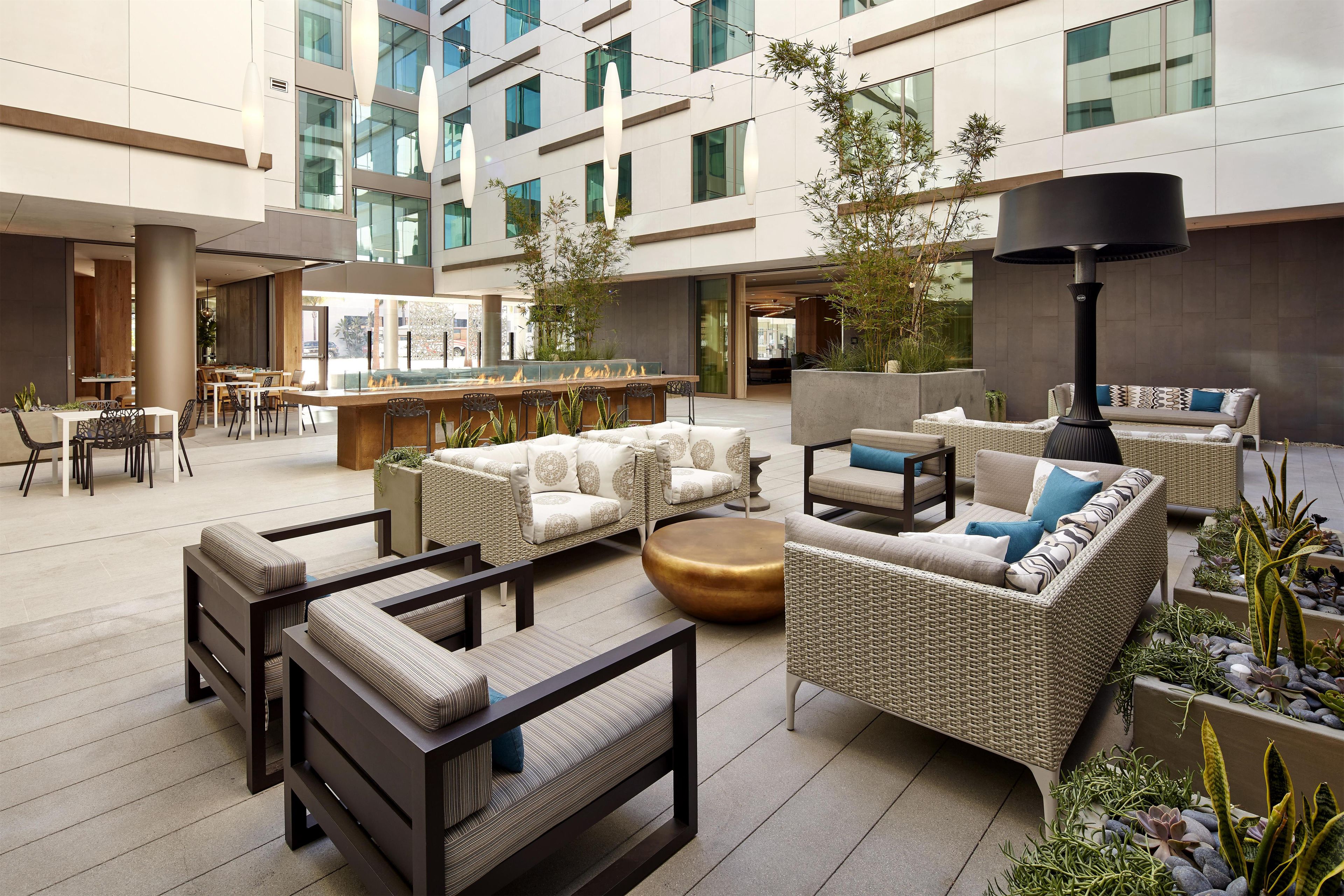A modern outdoor lounge area with seating arrangements, a bar, and a water feature.