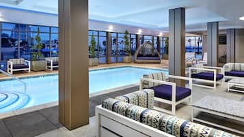 A modern indoor pool area with seating arrangements and large windows offering views of the cityscape.