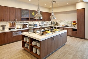 Una cocina moderna con armarios de madera, encimera de mármol y una isla central con una presentación de alimentos.