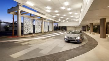 A modern building entrance with a car parked inside, featuring a patterned decorative wall and a tiled floor.