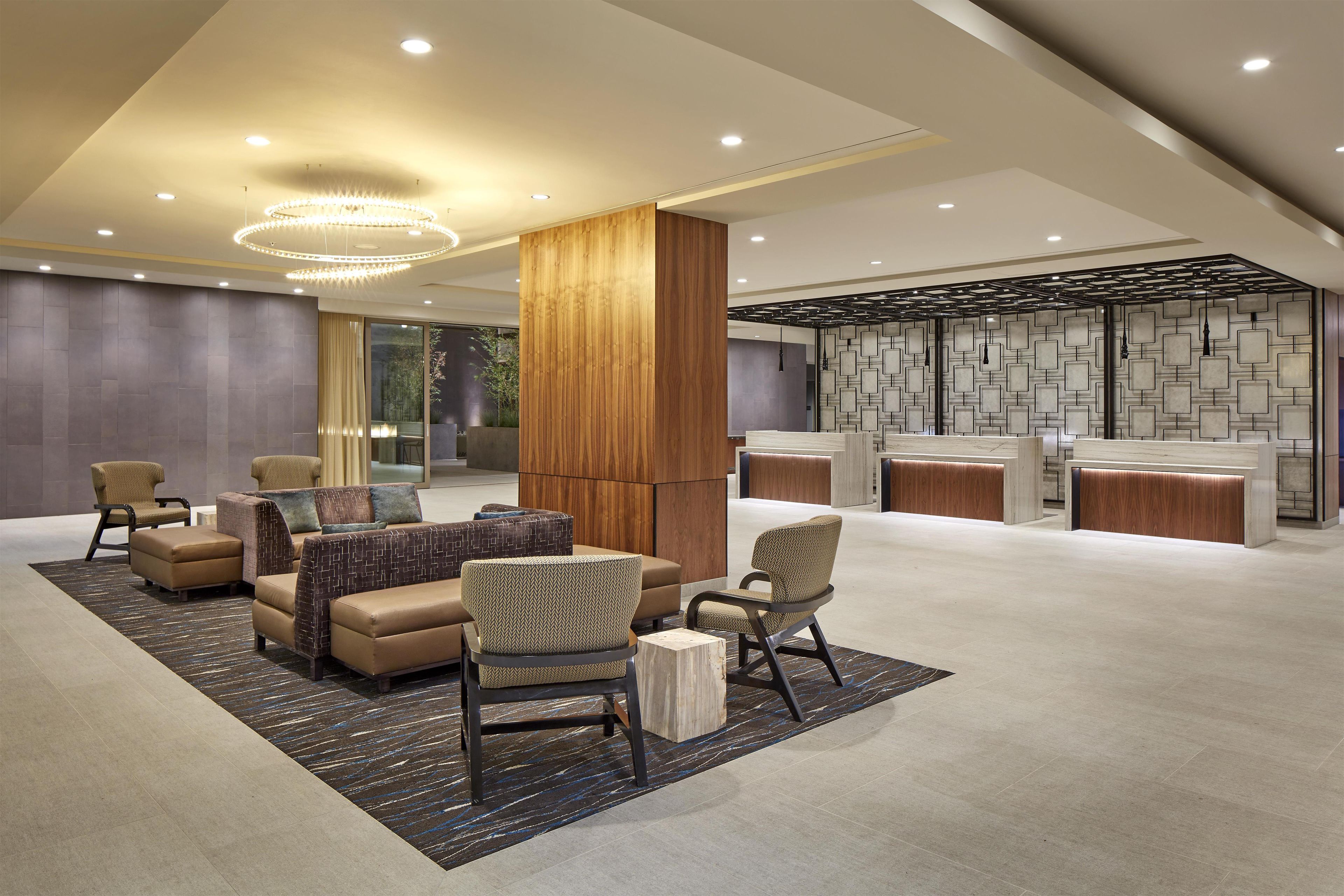 Een moderne lobby met zitplaatsen, een receptiebalie en een decoratieve wand.