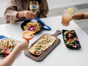 Una mesa de comedor con diversos platos, entre ellos tacos, una ensalada y una pizza.