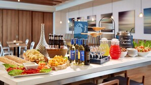 A buffet table with various food items, beverages, and a sign indicating 'Tasty Soup Broccoli Cheddar'.