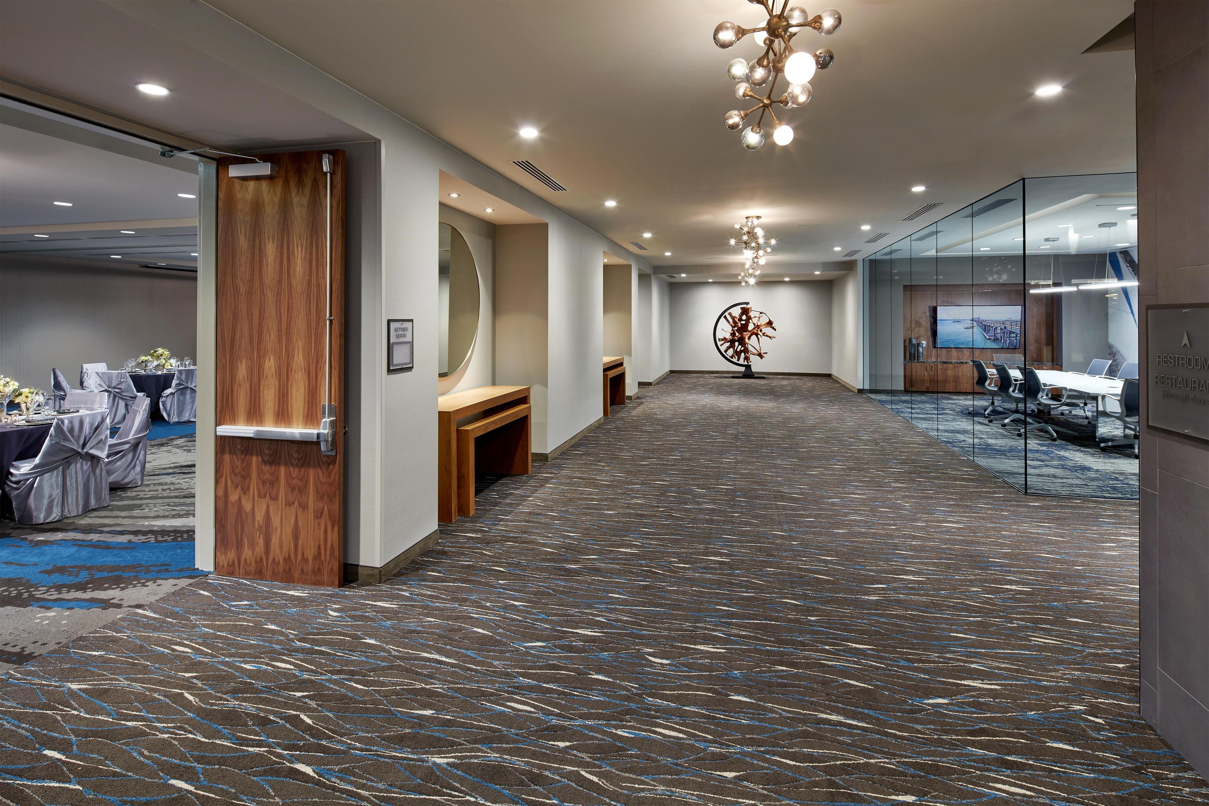 A hotel lobby with a long corridor, seating area, and a conference room.