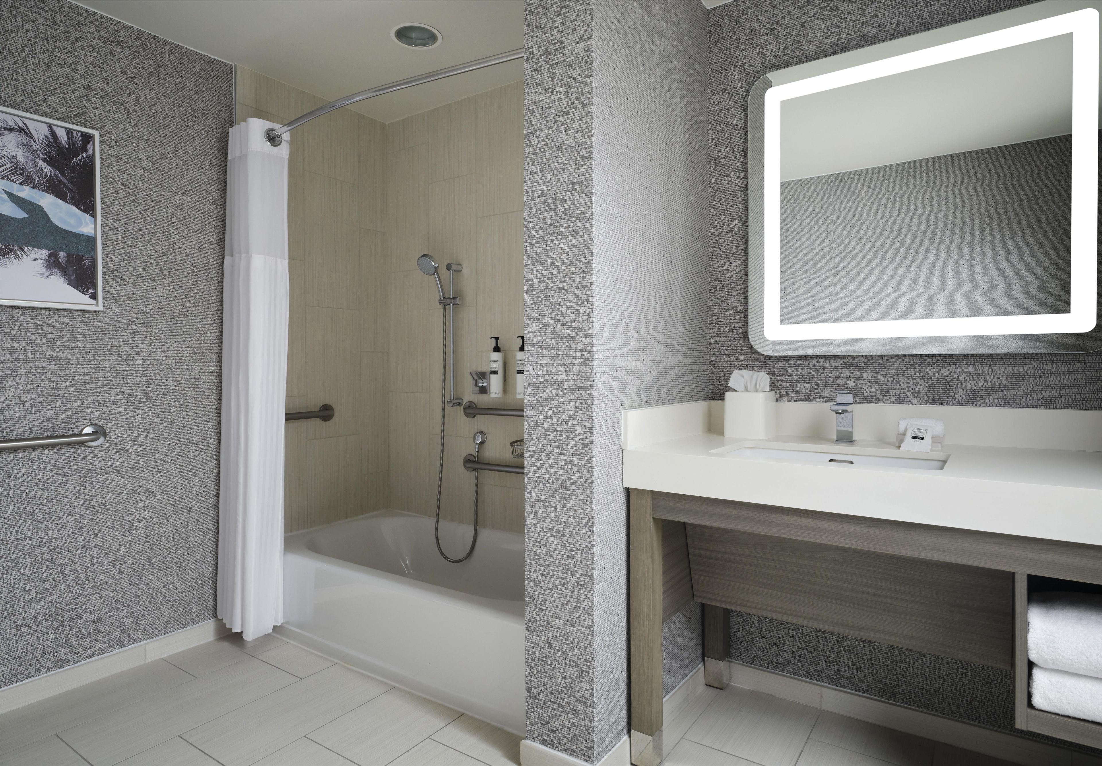 Une salle de bain moderne équipée d’une douche, d’une baignoire et d’un grand miroir au-dessus du lavabo.
