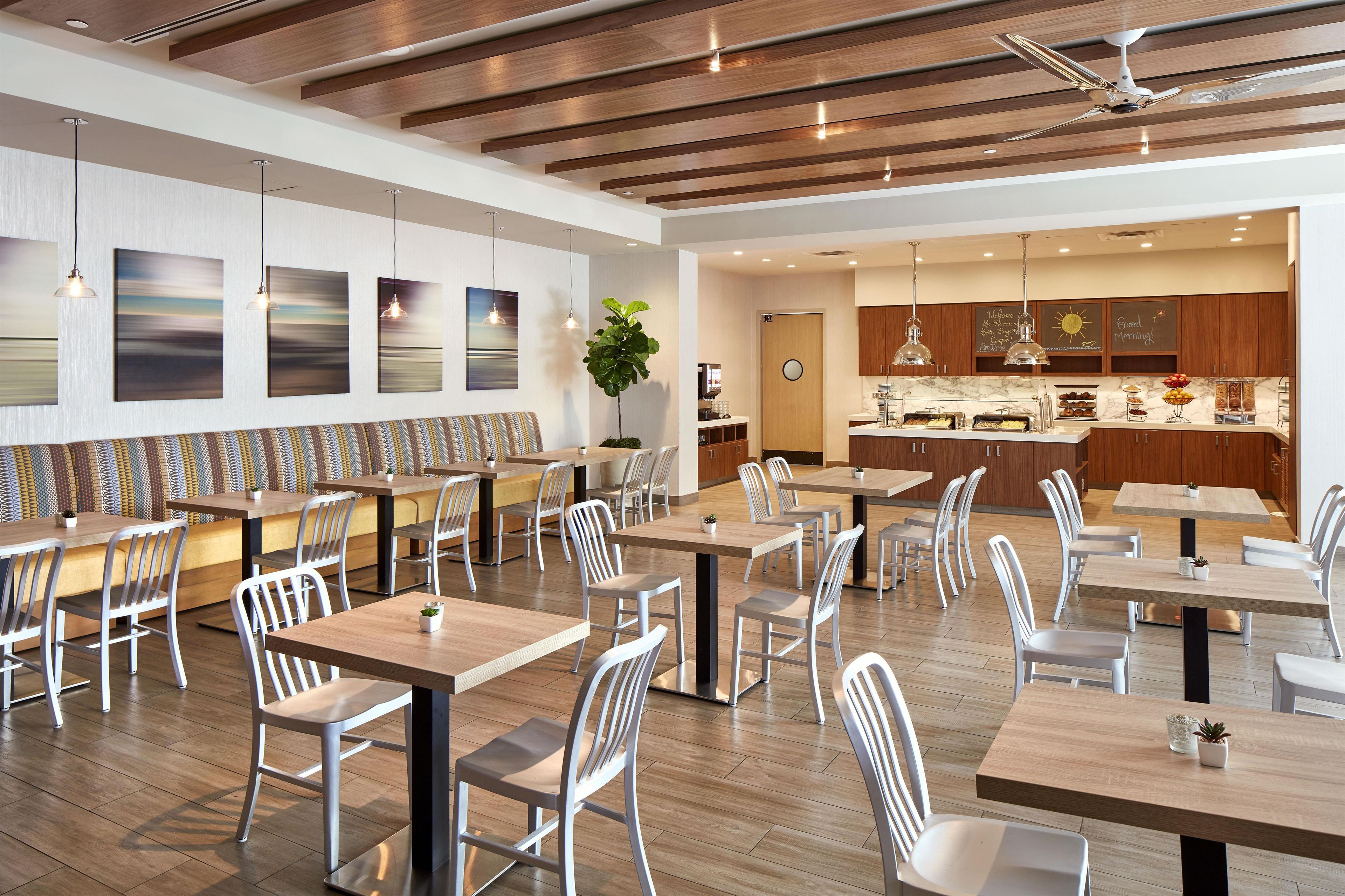 Un restaurant moderne avec des poutres en bois au plafond, des chaises blanches et un espace bar.