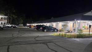 Ein Parkplatz mit mehreren Autos und einem Gebäude mit beleuchteten Fenstern.