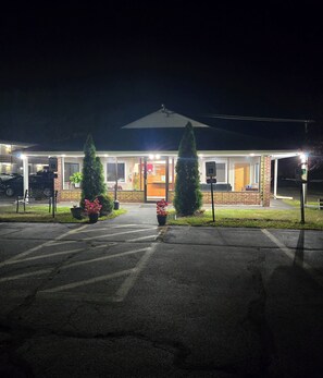 Un edificio bien iluminado con recepción, estacionamiento y una zona de estar al aire libre techada.