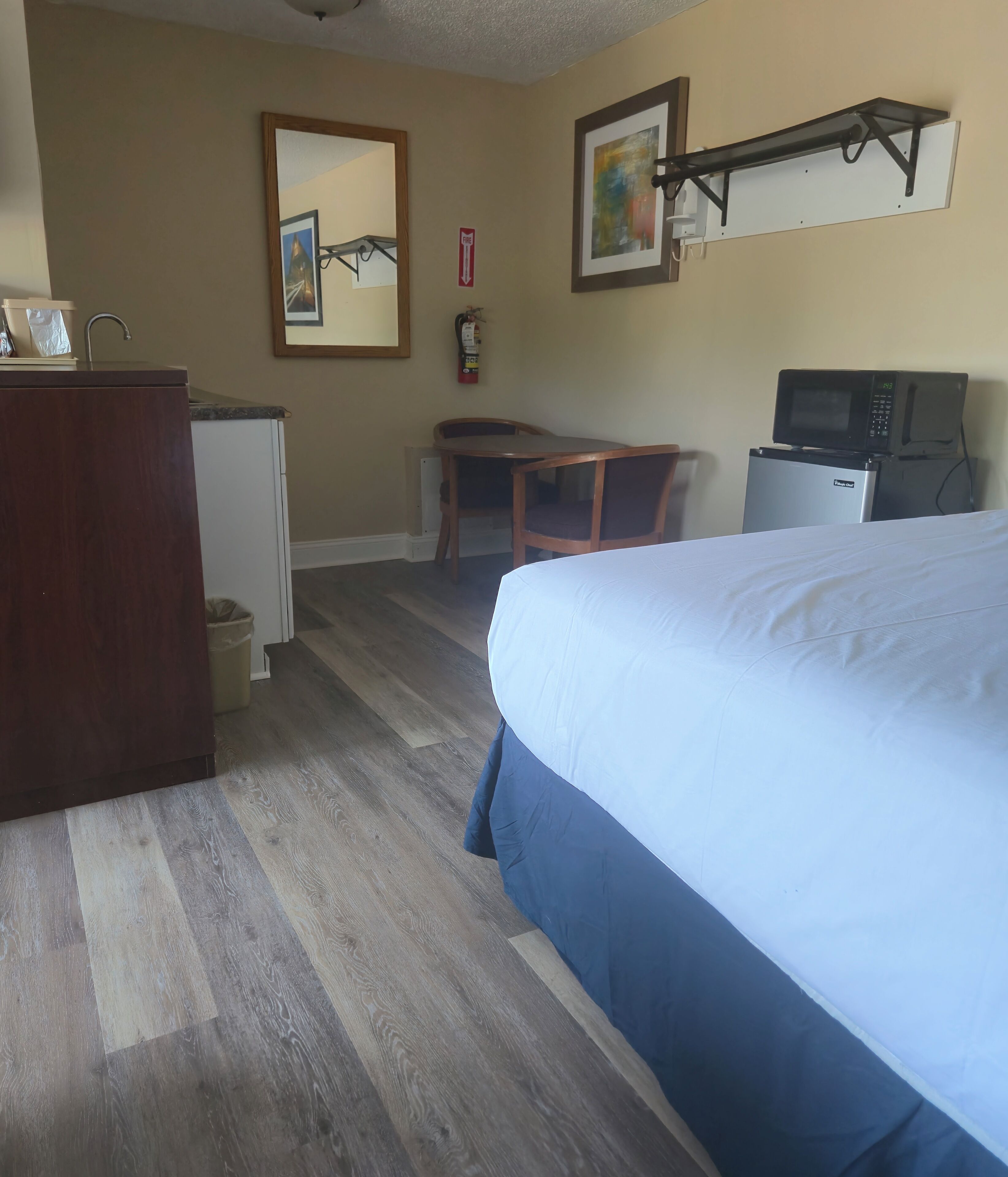 Habitación de hotel con cama, escritorio, silla, microondas y refrigerador.