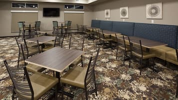 A conference room with multiple tables and chairs, a large screen, and a patterned carpet.