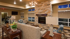 A living room with a stone fireplace, a sofa, and a coffee table. - GrandStay Hotel and Suites (Valley City)