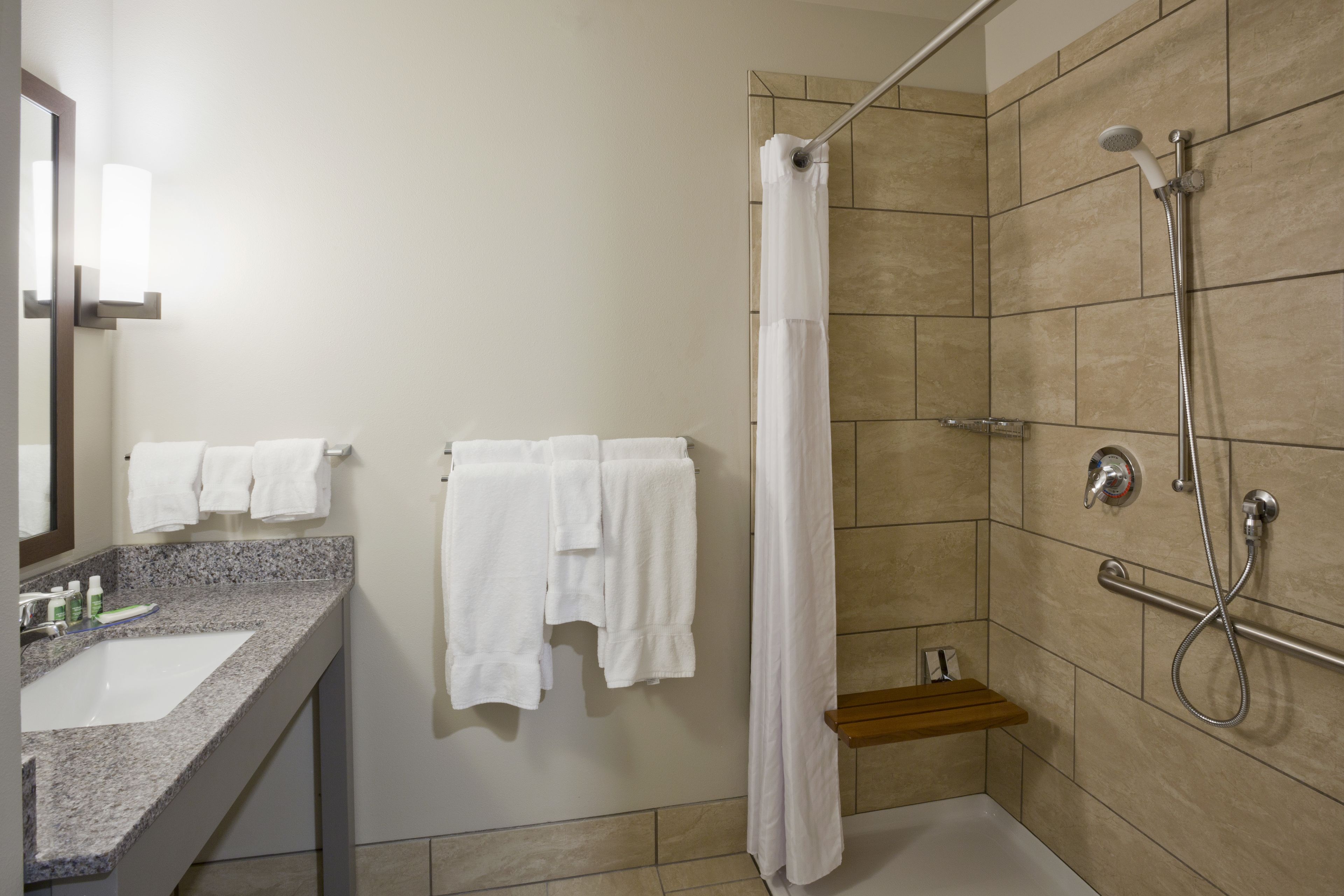 A bathroom with a shower, a sink, and a mirror.