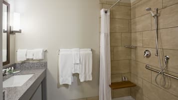 A bathroom with a shower, a sink, and a mirror.