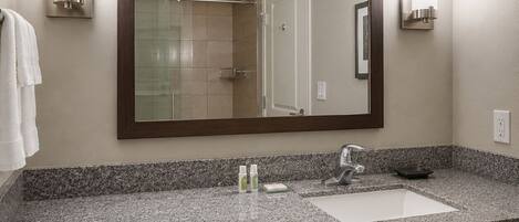 A bathroom with a large mirror, a sink, and two wall-mounted lights.