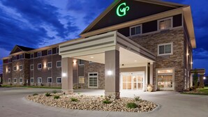 A modern hotel with a stone facade, a covered entrance, and a well-lit exterior. - GrandStay Hotel and Suites (Valley City)