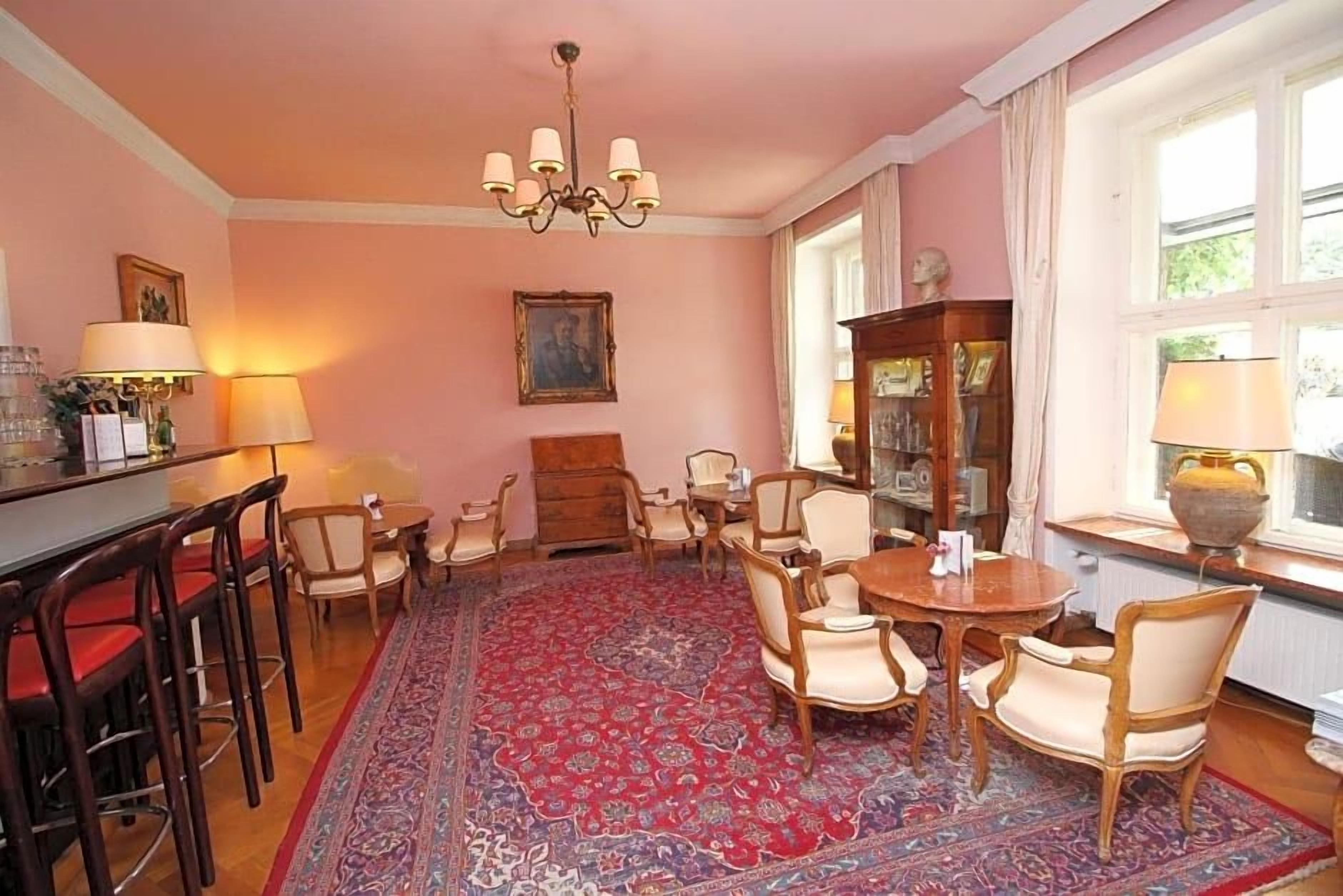 Ein Zimmer mit einem runden Tisch, Stühlen, einer Bar und einem großen Teppich.