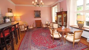A room with a round table, chairs, a bar area, and a large rug. - Hotel Leopold (Munich)