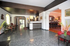 A lobby with a reception desk, seating area, and a dining space. - Hotel Leopold (Munich)