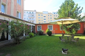 A courtyard with a lawn, a table with chairs, and a large umbrella.