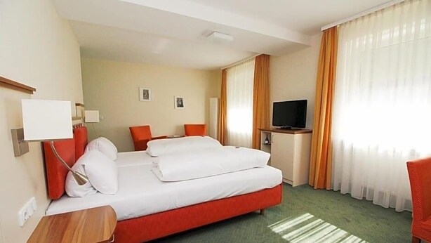 Een hotelkamer met een bed, een televisie, een bureau en een stoel.