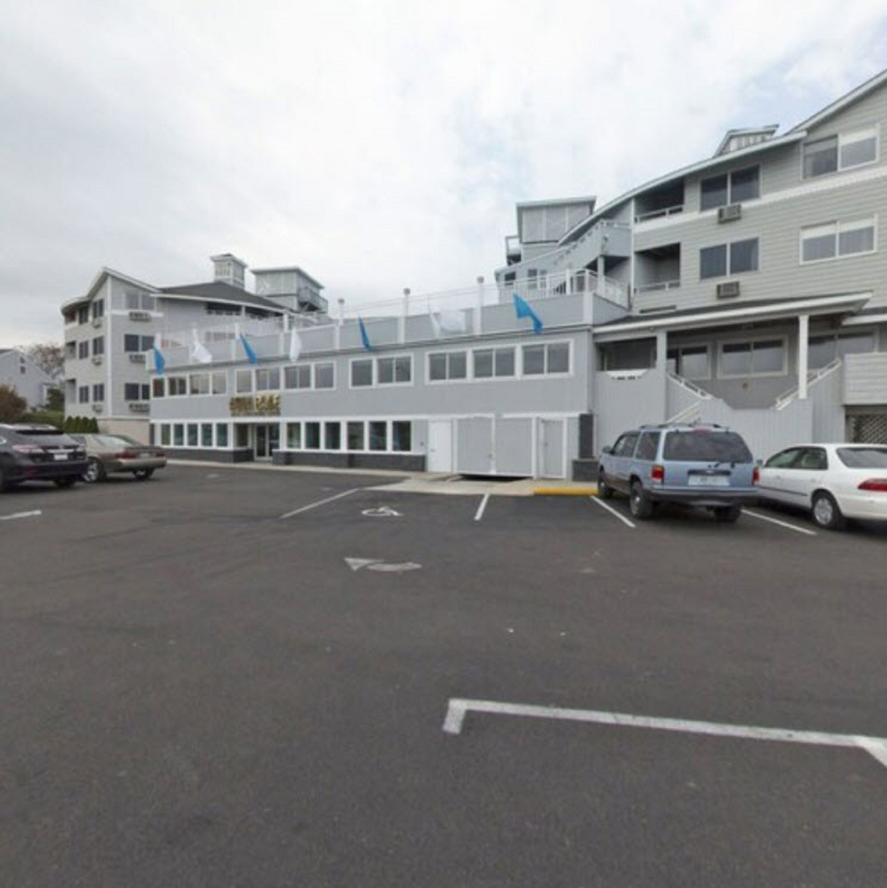 A modern building with a parking lot, marked parking spaces, and a blue directional sign.