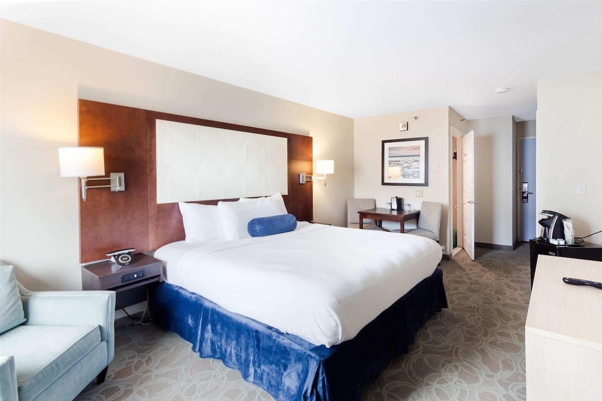A hotel room with a large bed, bedside tables, a desk, and a chair.