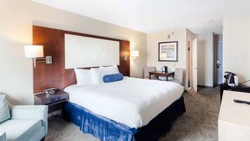 Ein Hotelzimmer mit einem großen Bett, Nachttischen, einem Schreibtisch und einem Sessel.