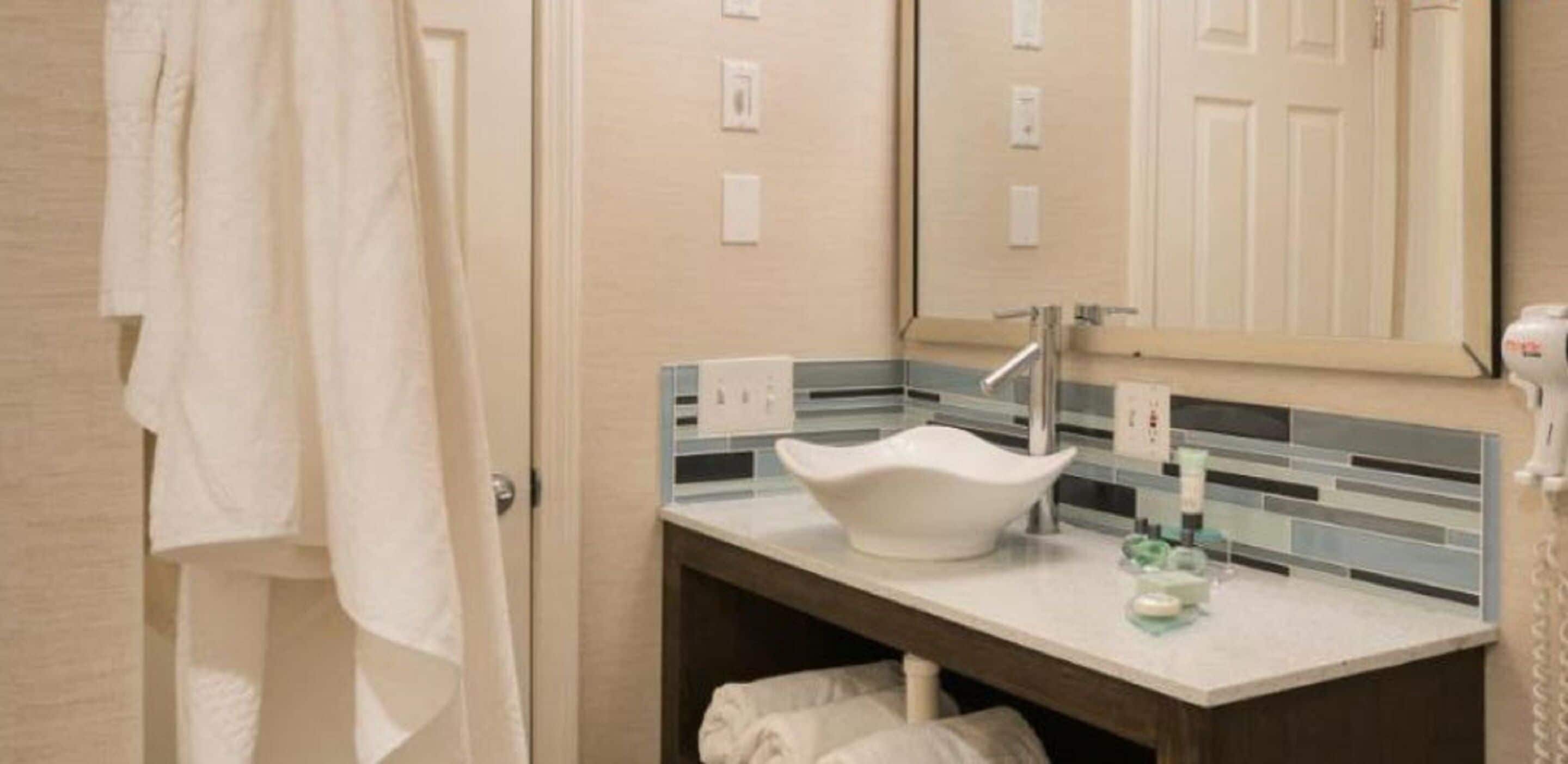 A bathroom with a white sink, a mirror, and a towel rack.