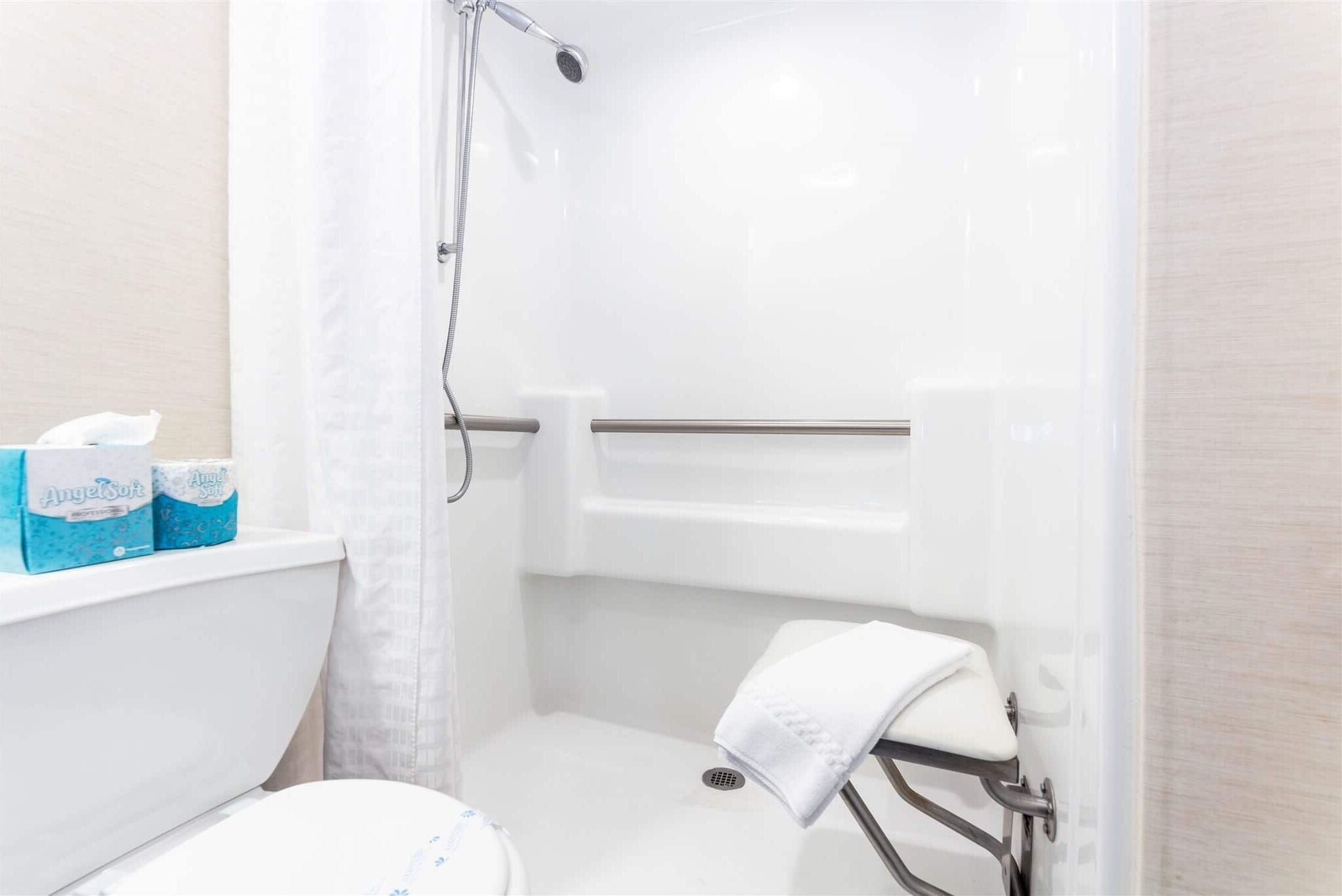 Un baño con ducha, inodoro y un perchero para toallas.