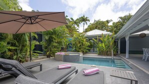 A poolside area with lounge chairs, a pool, and tropical plants. - Majesty Palm (Saint-François)