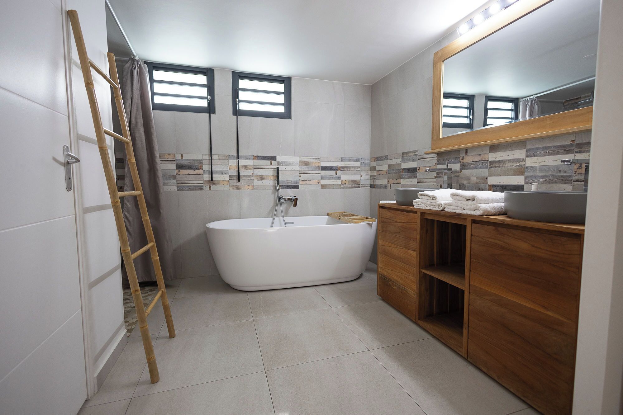 Une salle de bain moderne avec une baignoire sur pieds, un meuble-lavabo en bois et un grand miroir.