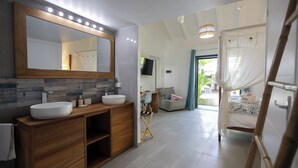 A modern bathroom with a large mirror, two sinks, and a vanity with storage. - Majesty Palm (Saint-François)